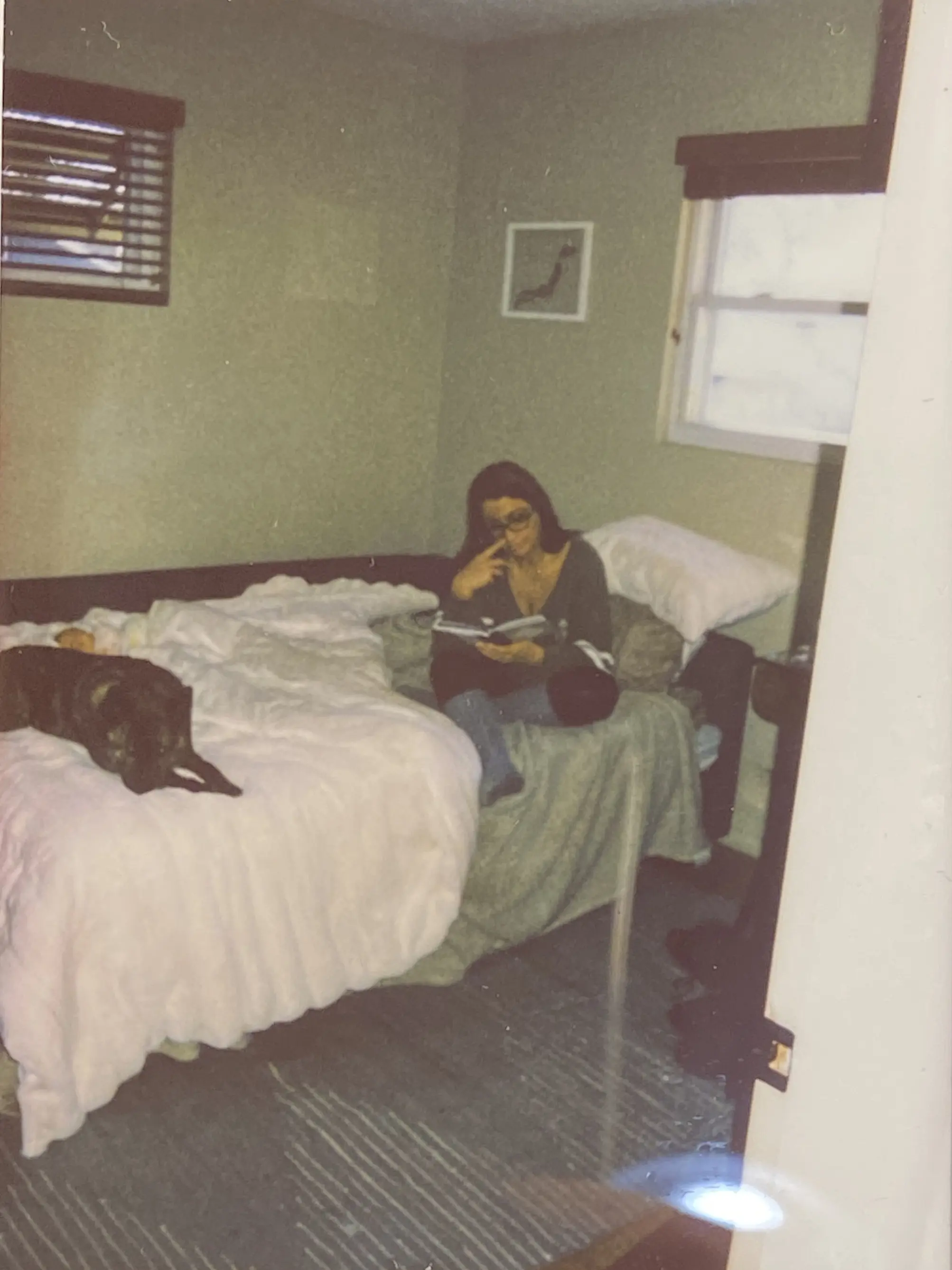 Jessica reading a book about dad while Maya sleeps with Velo guarding